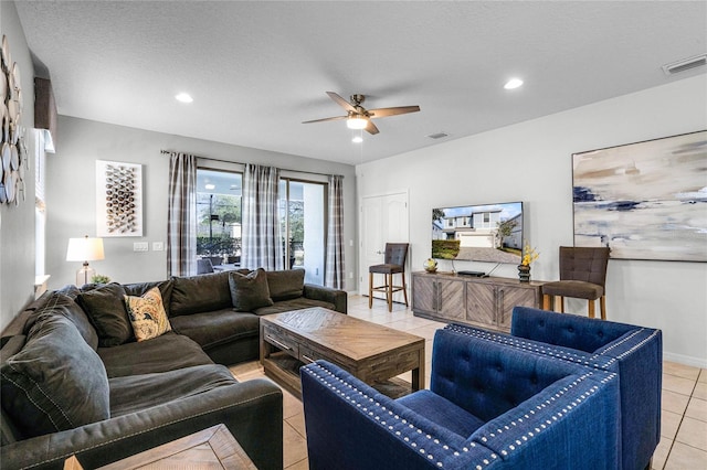 living room featuring ceiling fan, a textured ceiling, and light tile patterned floors