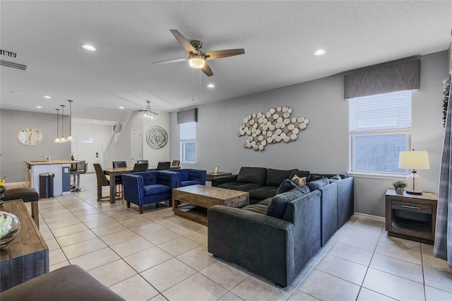 living room with ceiling fan, a textured ceiling, and light tile patterned floors