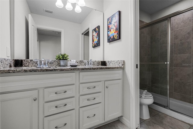 bathroom featuring tile patterned flooring, vanity, a shower with shower door, and toilet