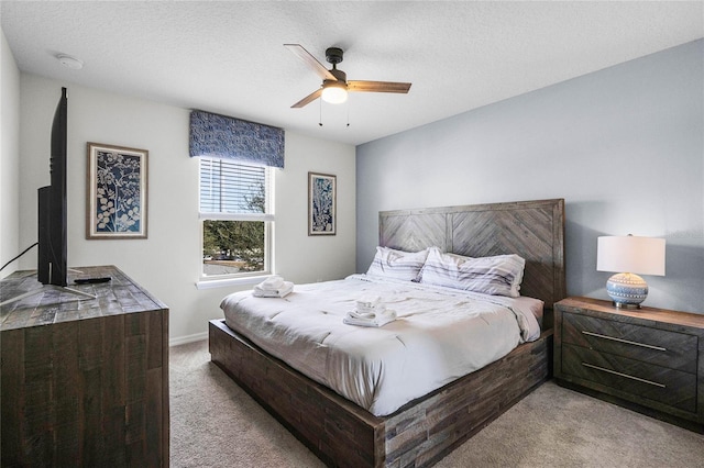 bedroom featuring ceiling fan, light carpet, and a textured ceiling