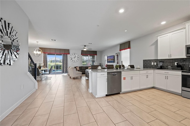 kitchen featuring decorative light fixtures, white cabinets, backsplash, kitchen peninsula, and stainless steel appliances