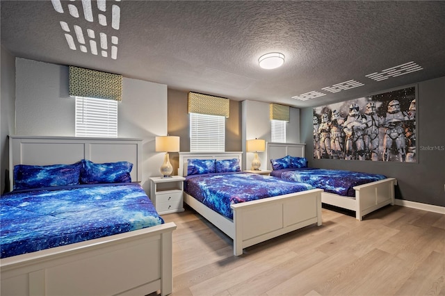 bedroom with multiple windows, light hardwood / wood-style flooring, and a textured ceiling