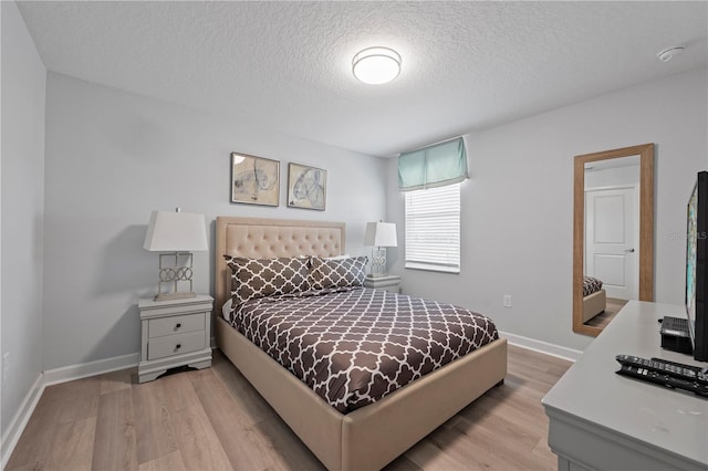 bedroom featuring light hardwood / wood-style floors and a textured ceiling