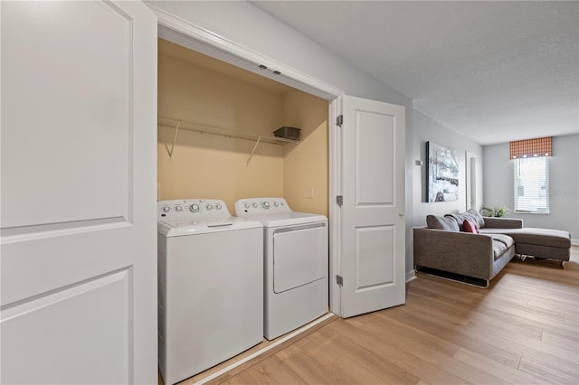 clothes washing area featuring independent washer and dryer, a textured ceiling, and light wood-type flooring