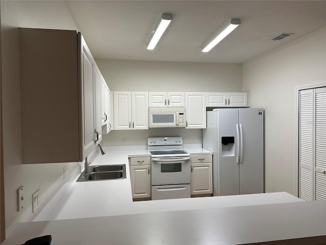 kitchen featuring sink, white cabinets, white appliances, and kitchen peninsula