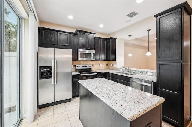 kitchen featuring decorative light fixtures, sink, a center island, stainless steel appliances, and light stone countertops