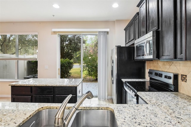 kitchen with light stone counters, appliances with stainless steel finishes, sink, and backsplash