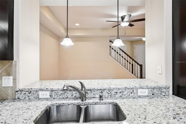 kitchen featuring sink, decorative light fixtures, light stone countertops, and ceiling fan