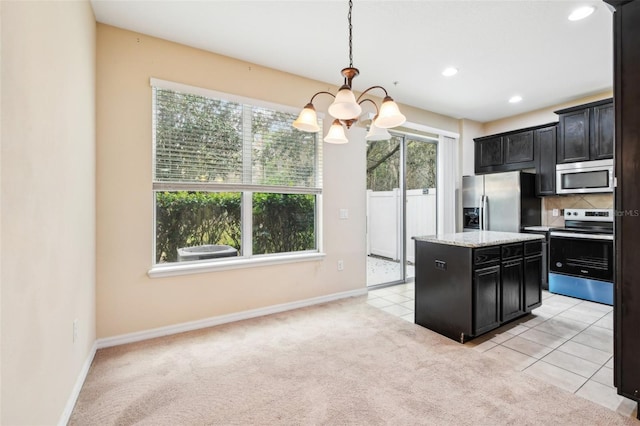 kitchen with pendant lighting, appliances with stainless steel finishes, tasteful backsplash, a kitchen island, and light colored carpet