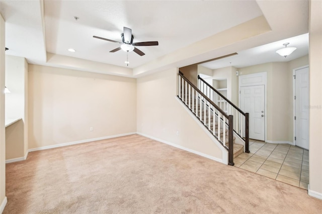 interior space with light colored carpet, ceiling fan, and a tray ceiling