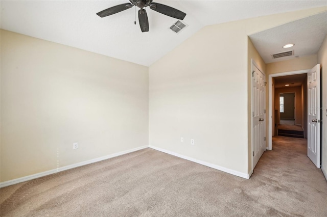 carpeted spare room featuring vaulted ceiling and ceiling fan