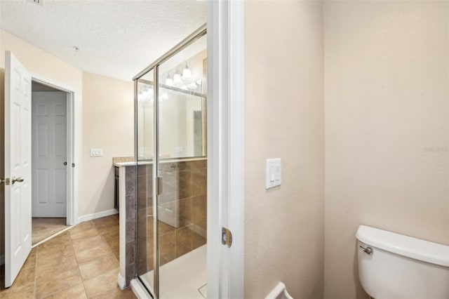 bathroom featuring tile patterned floors, toilet, a shower with door, and a textured ceiling