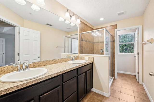 bathroom with vanity, tile patterned floors, a shower with door, and a textured ceiling