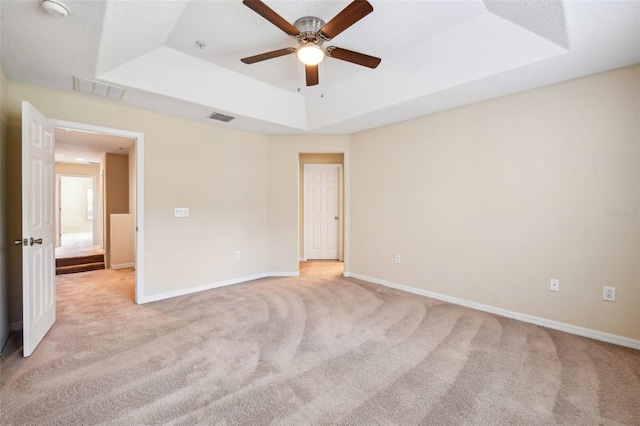 carpeted empty room with a tray ceiling and ceiling fan