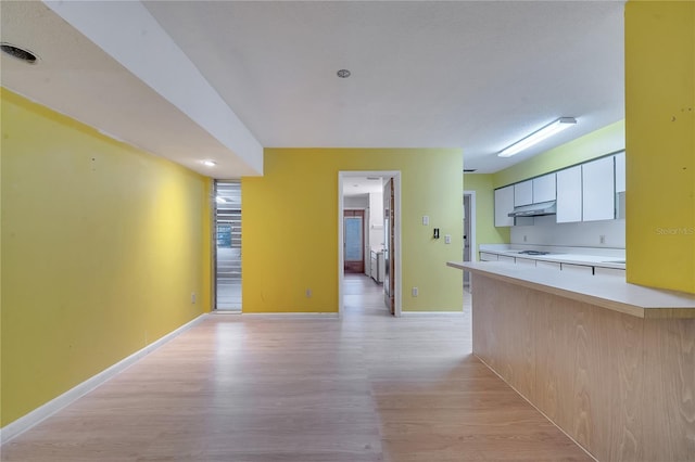 kitchen featuring white cooktop, light wood-type flooring, and white cabinets