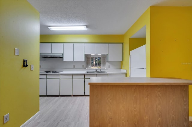 kitchen featuring sink, white appliances, white cabinetry, a textured ceiling, and light wood-type flooring