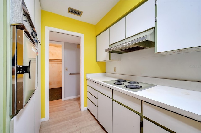 kitchen featuring refrigerator, white electric stovetop, white cabinets, and light wood-type flooring