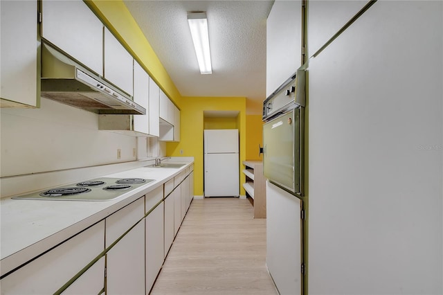 kitchen featuring sink, a textured ceiling, light wood-type flooring, white appliances, and white cabinets