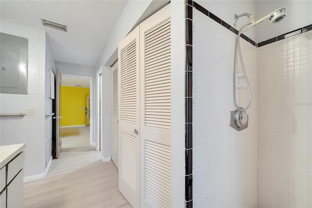 hall featuring light hardwood / wood-style flooring, electric panel, and a textured ceiling