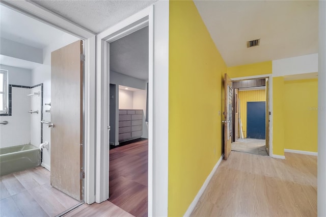 hallway with a textured ceiling and light wood-type flooring