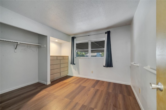 unfurnished bedroom featuring wood-type flooring, a textured ceiling, and a closet