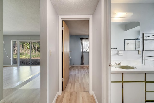 hall featuring light hardwood / wood-style floors, sink, and a textured ceiling