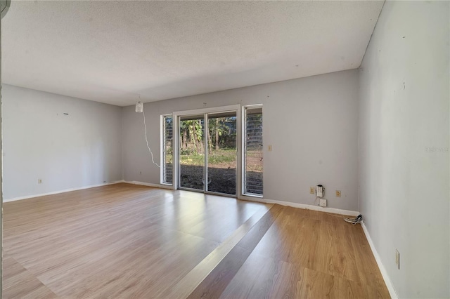 empty room with light hardwood / wood-style floors and a textured ceiling