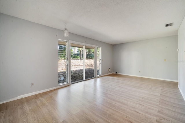 empty room with a textured ceiling and light hardwood / wood-style floors