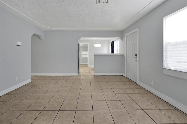 unfurnished room featuring a textured ceiling and light tile patterned flooring