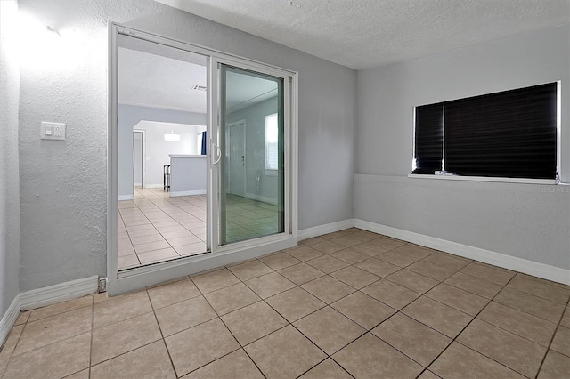 spare room with a textured ceiling and light tile patterned flooring