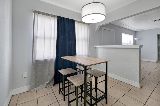 dining room featuring a textured ceiling, light tile patterned floors, visible vents, and baseboards