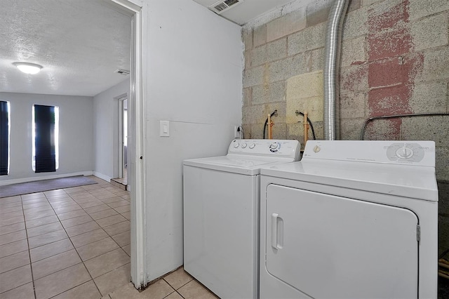 laundry area with laundry area, light tile patterned floors, visible vents, washer and clothes dryer, and a textured ceiling