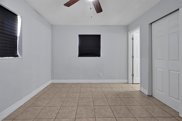 spare room with a ceiling fan, baseboards, and light tile patterned floors