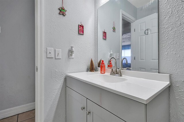 bathroom with baseboards, a textured wall, vanity, and tile patterned floors