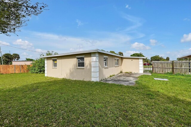 back of property featuring a yard, a patio area, fence, and stucco siding