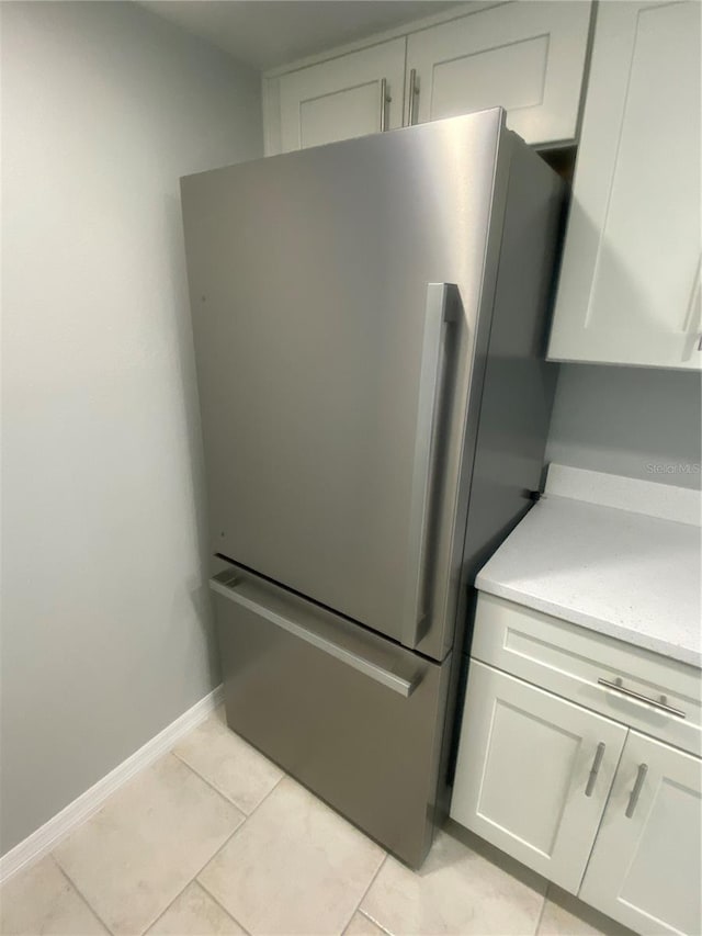 kitchen with white cabinetry, light tile patterned floors, and stainless steel fridge