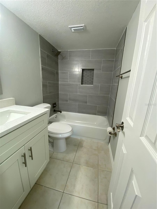 full bathroom featuring tiled shower / bath combo, vanity, a textured ceiling, tile patterned floors, and toilet