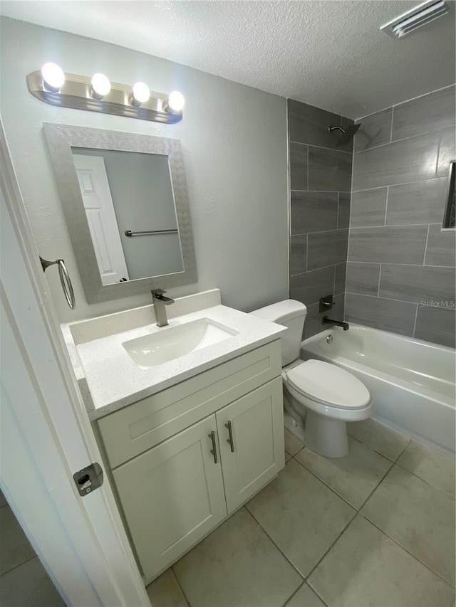 full bathroom featuring tiled shower / bath, vanity, toilet, tile patterned floors, and a textured ceiling