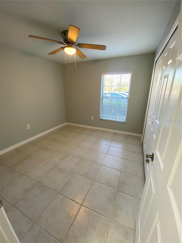 tiled spare room with ceiling fan