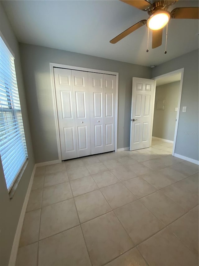 unfurnished bedroom featuring light tile patterned flooring, ceiling fan, and a closet