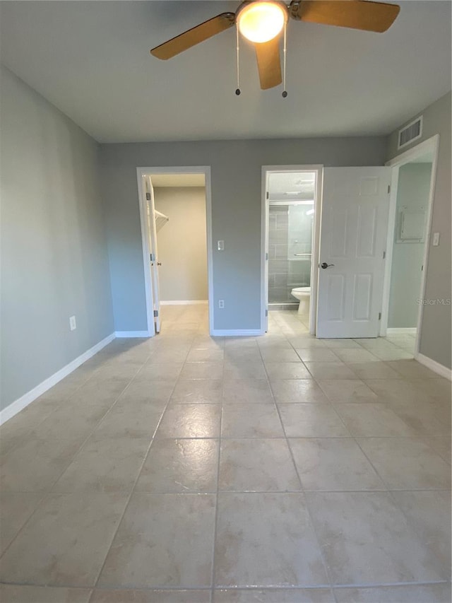 unfurnished bedroom featuring light tile patterned floors, ensuite bath, ceiling fan, a spacious closet, and a closet