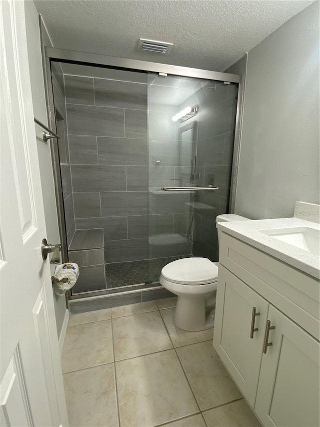 bathroom featuring walk in shower, tile patterned floors, toilet, a textured ceiling, and vanity