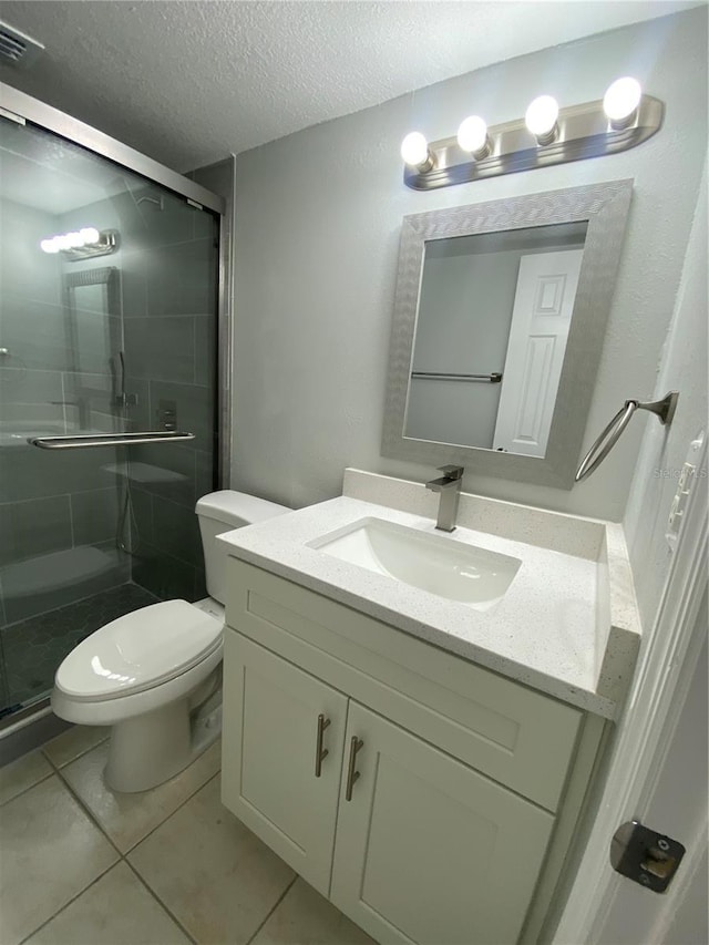 bathroom featuring vanity, an enclosed shower, toilet, tile patterned floors, and a textured ceiling