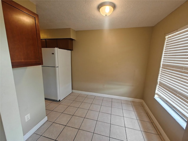 kitchen featuring white refrigerator, light tile patterned flooring, and a textured ceiling