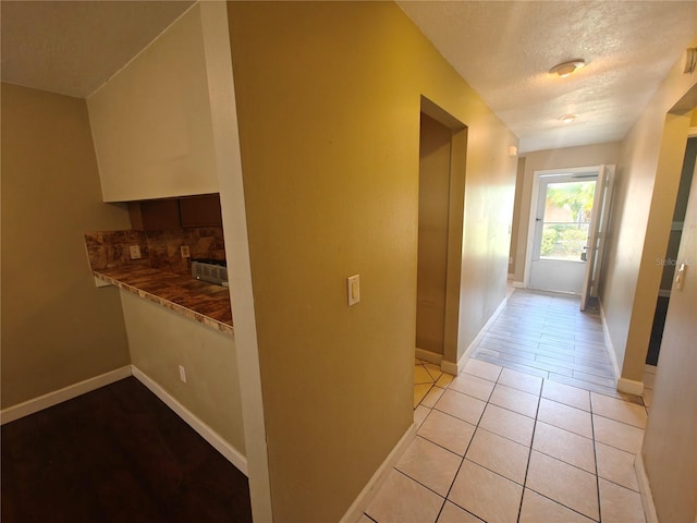 hallway featuring light tile patterned floors and a textured ceiling