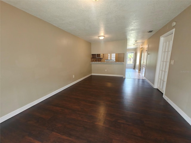 spare room with a textured ceiling and dark hardwood / wood-style flooring