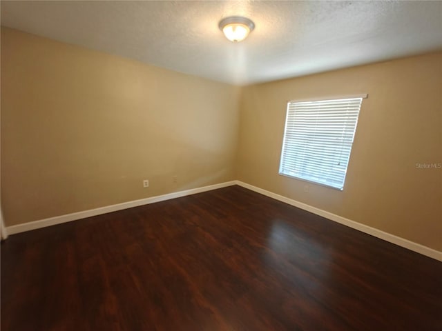 empty room featuring dark hardwood / wood-style flooring and a textured ceiling