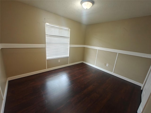 spare room with dark hardwood / wood-style floors and a textured ceiling