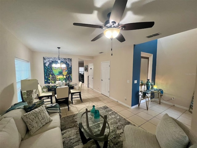 tiled living room with ceiling fan with notable chandelier