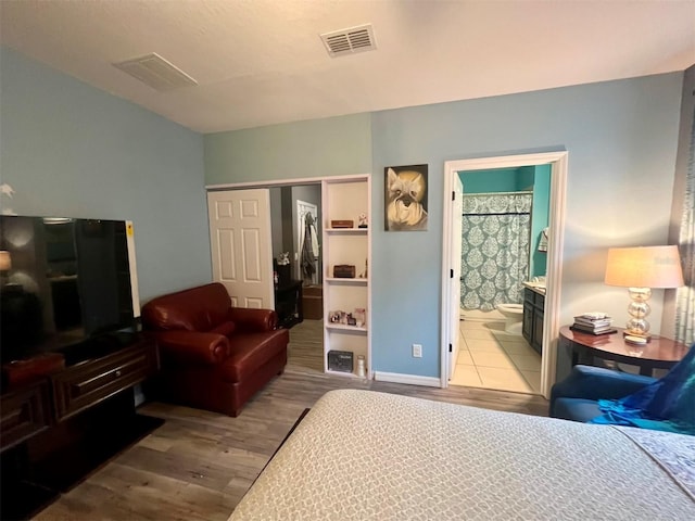 bedroom with a closet, ensuite bath, and light hardwood / wood-style flooring